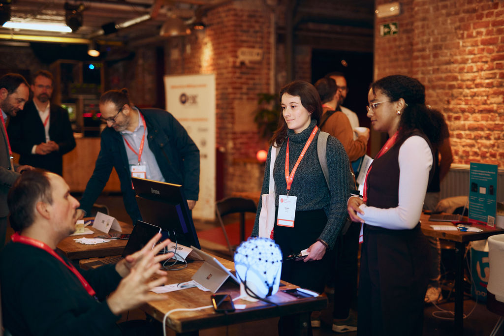 Two women standing in front of a table where a man sits